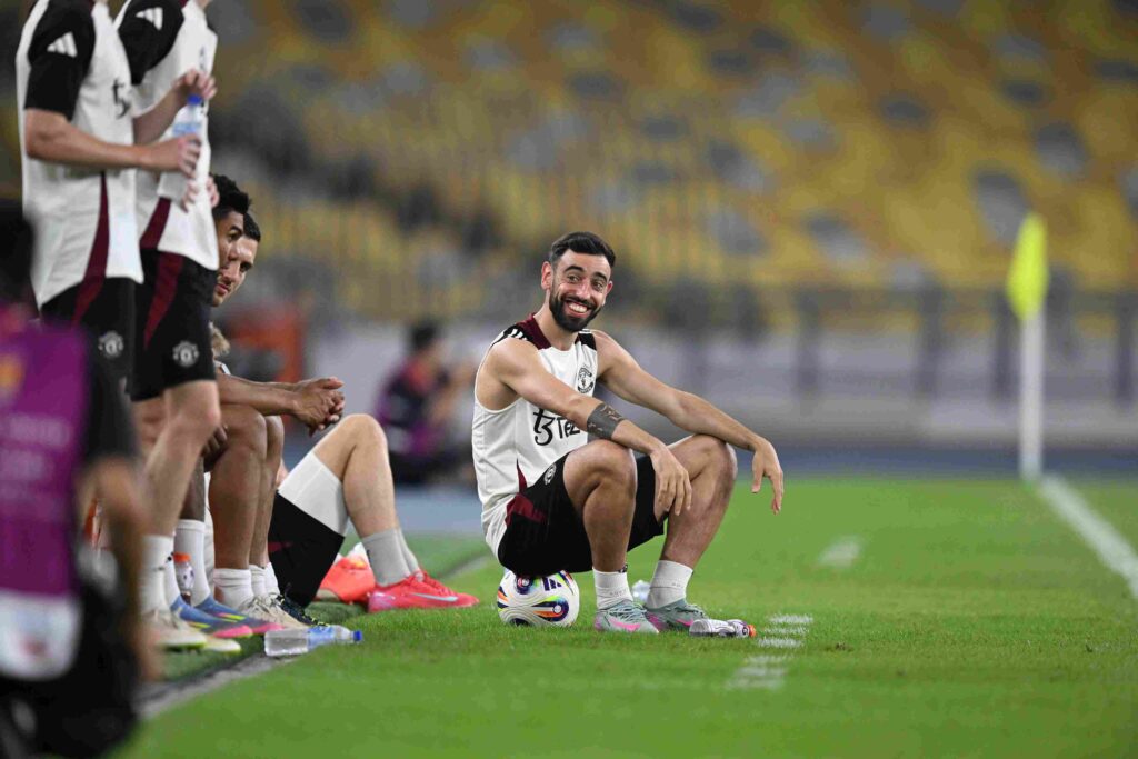 Μπρούνο Φερνάντες κάθεται σε μπάλα στο γήπεδο με τη φανέλα της Μάντεστερ Γιουνάιτεντ